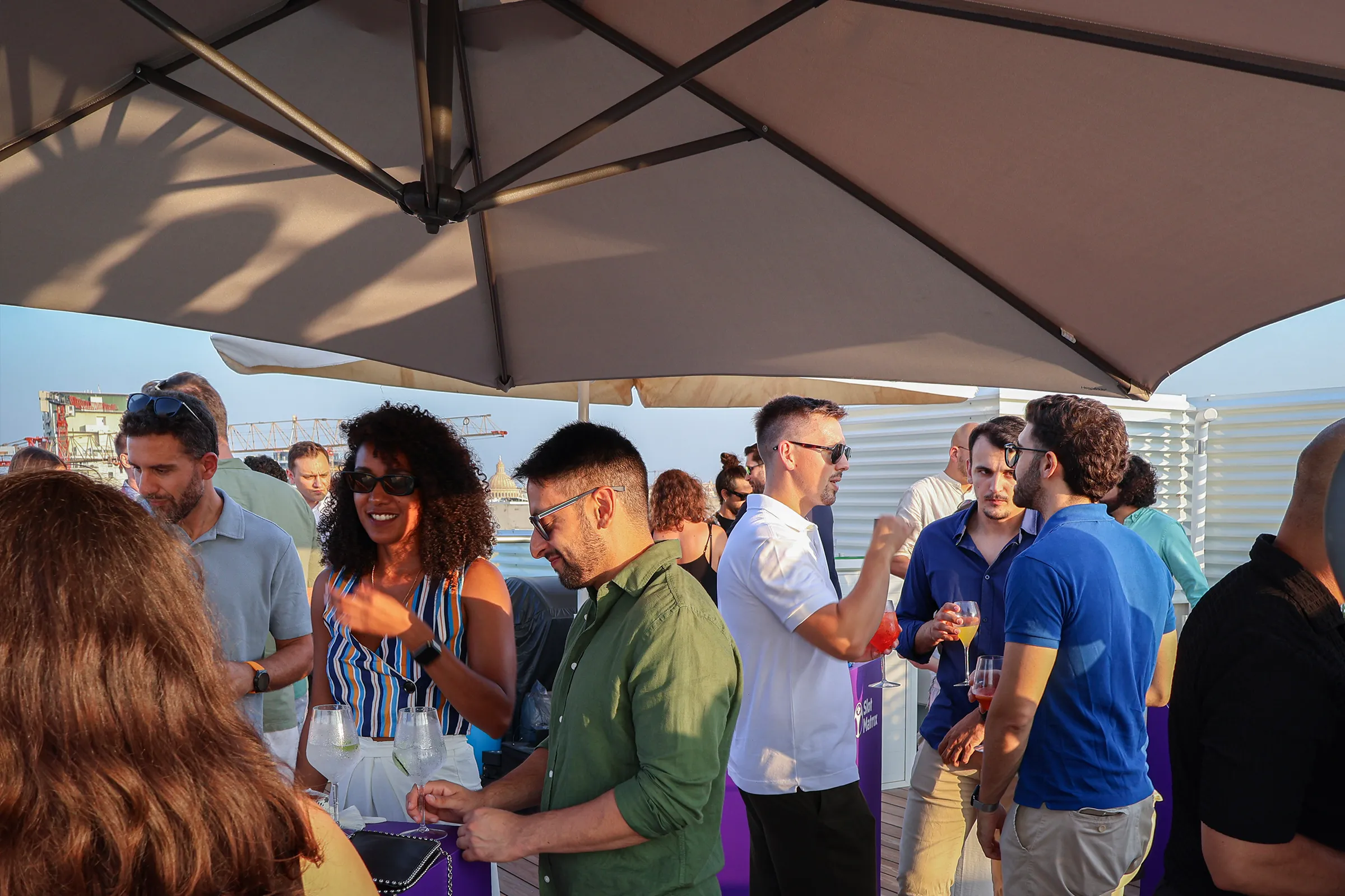Guests talking on the terrace at the SlotMatrix Open Day in Malta.