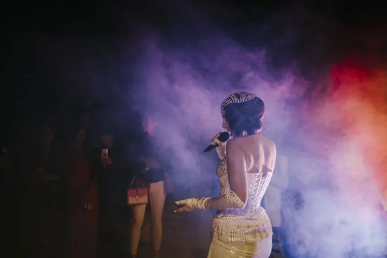 A performer beneath coloured stage lights · AFLOAT — Exclusive Networking at Sea